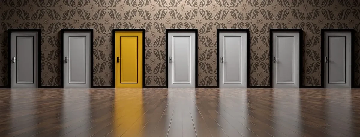 A wall with 7 doors, all white except for the third from left which is yellow