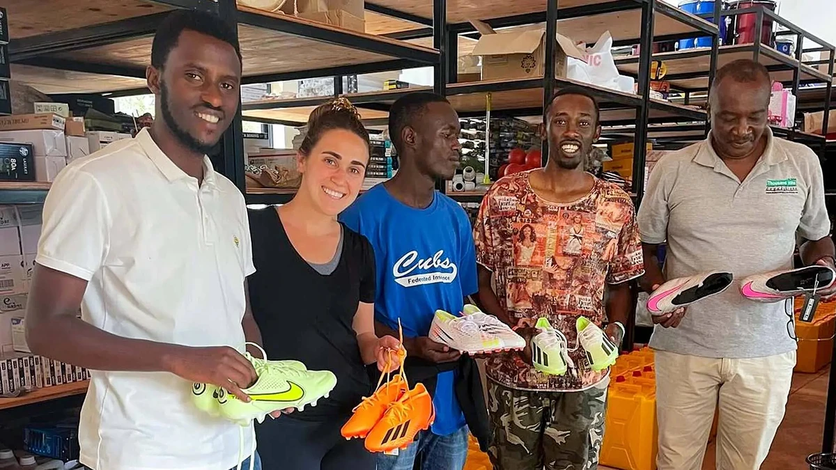 Sara Blau ’24 (second from left) gives donated cleats to recipients from the Agahozo-Shalom Youth Village in Rwanda. Her nonprofit, Game Changers, has distributed more than 100,000 pieces of sports equipment to children in need around the world.